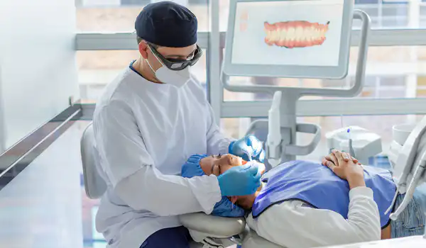 Male dentist about to put a transparent dental brace on a female patient